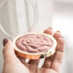 A delicate rose-shaped blush compact held in hand, perfect for enhancing your makeup collection.